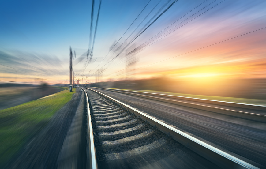 Railroad in motion at sunset. Railway station with motion blur effect against colorful sky, Industrial concept background. Railroad travel, railway tourism. Blurred railway. Transportation. Vintage