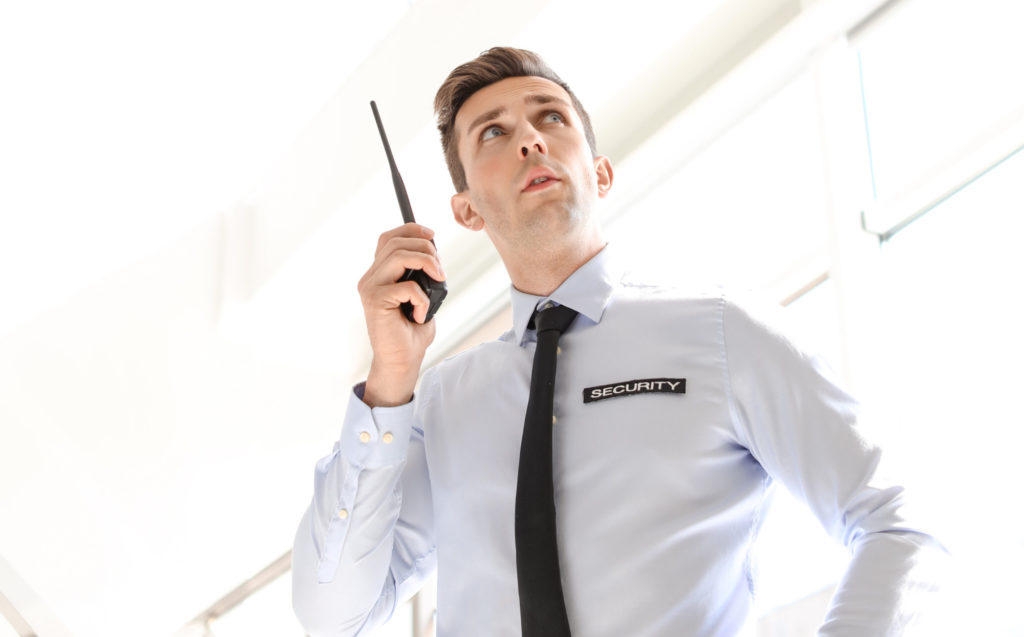Male security guard with portable radio transmitter indoors