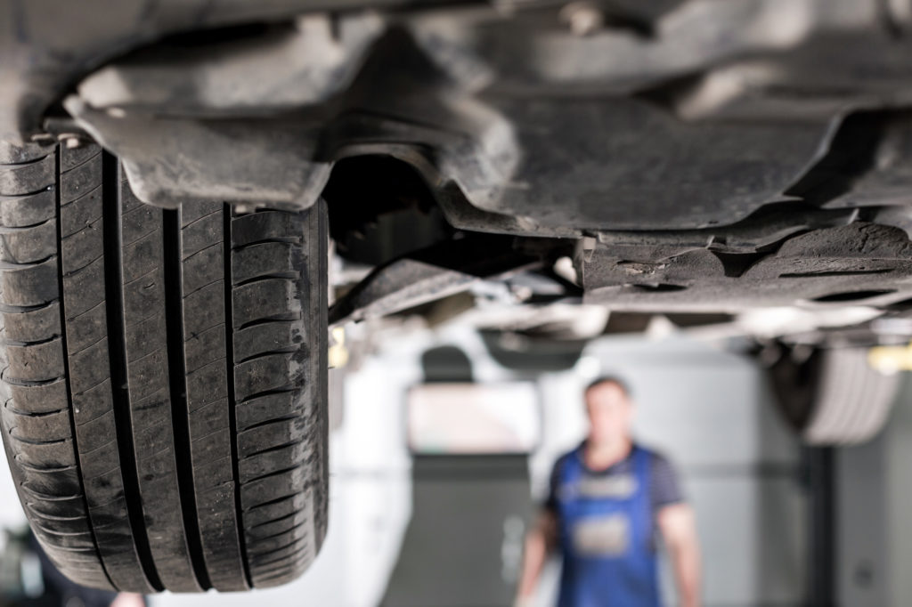 front car suspension. the garage mechanic raised the car on the lift.