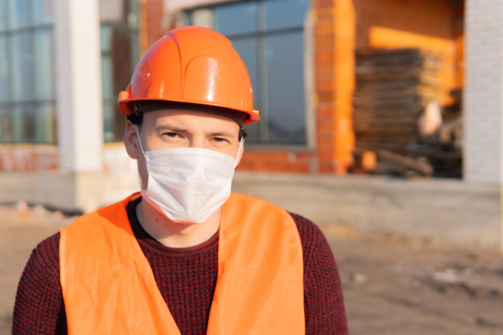 Portrait of male construction worker in medical mask and overalls