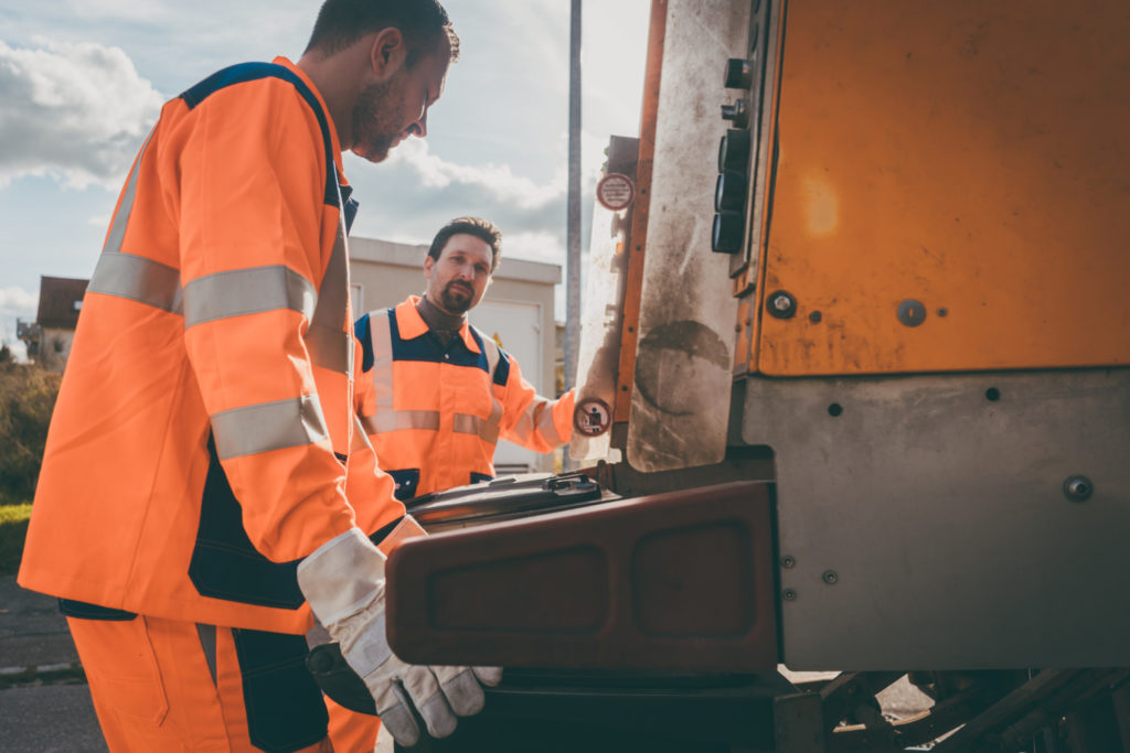 Garbage removal men working for a public utility emptying trash container