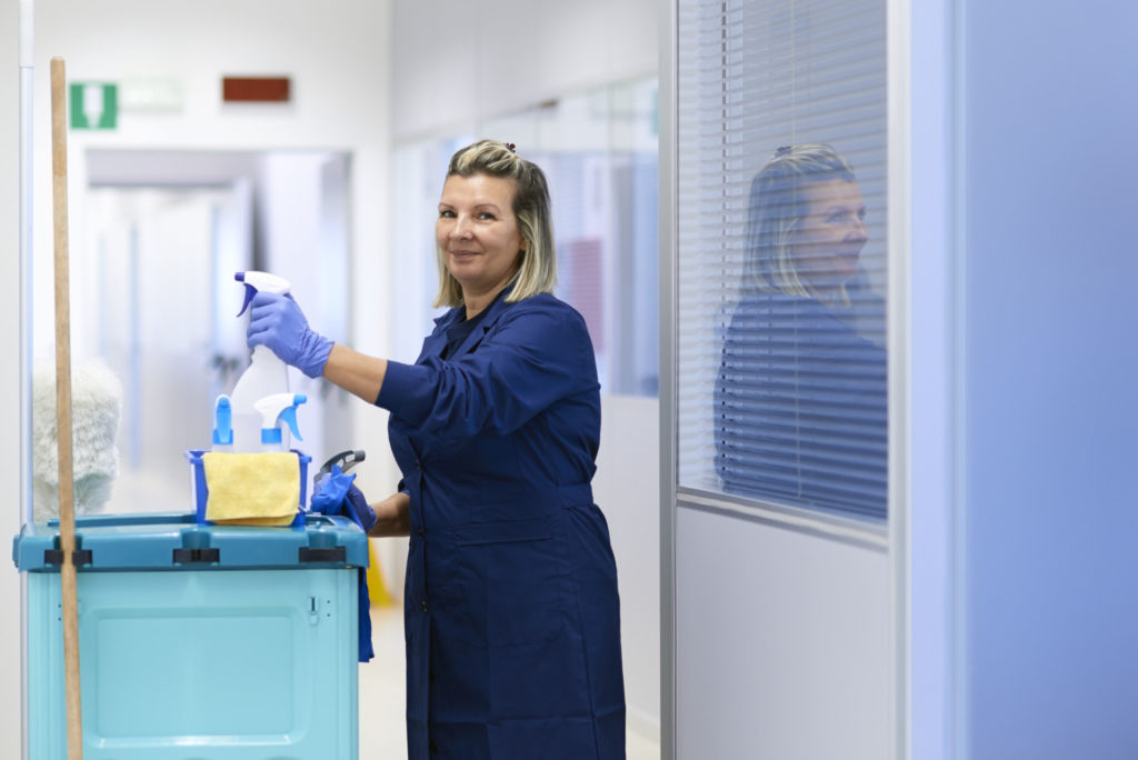 Women at work, portrait of happy professional female cleaner smiling and looking at camera in office. Three quarter length