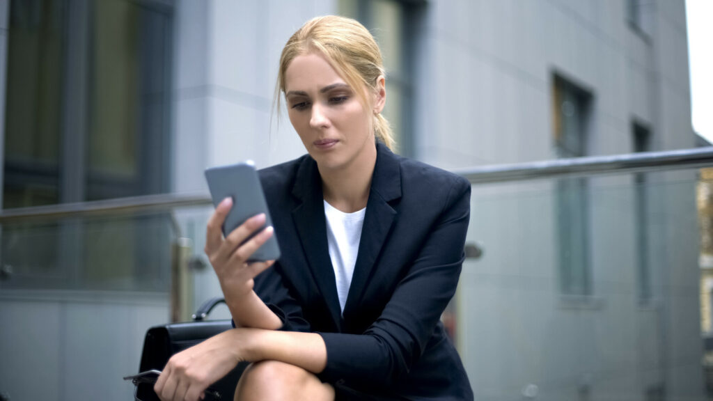 Businesswoman upset with message in smartphone, troubles at work, depression