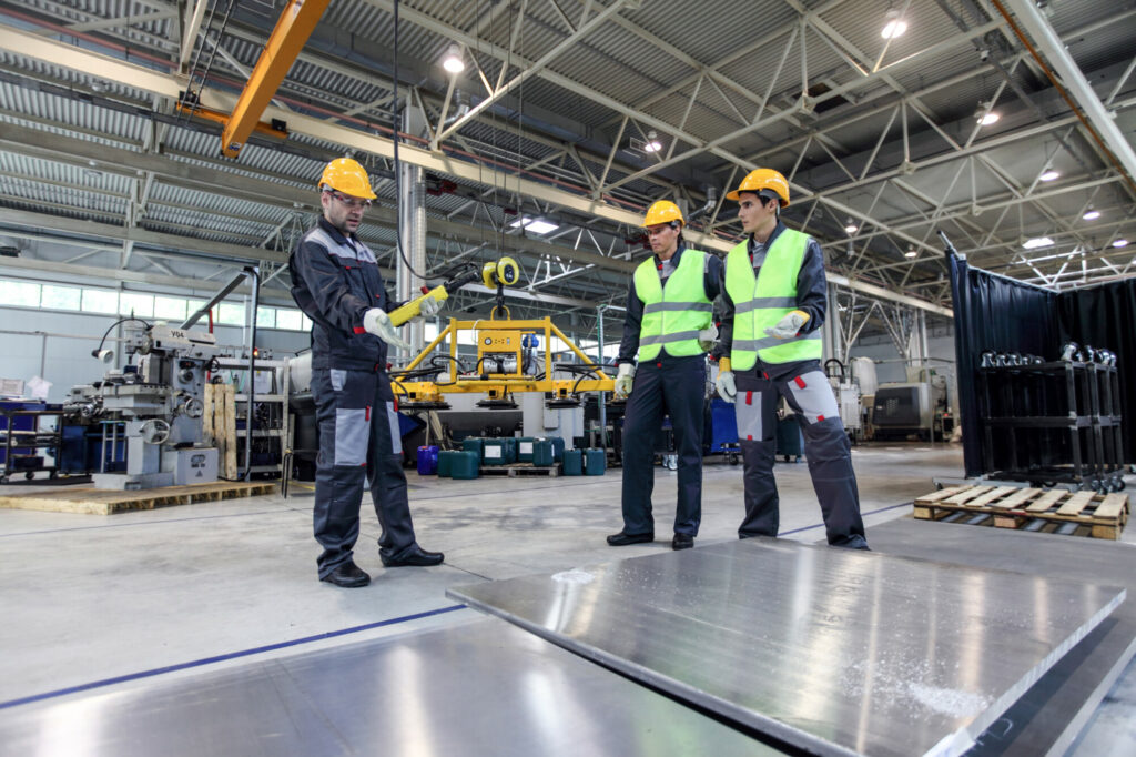 Workers standing near aluminium billets at CNC machine shop
