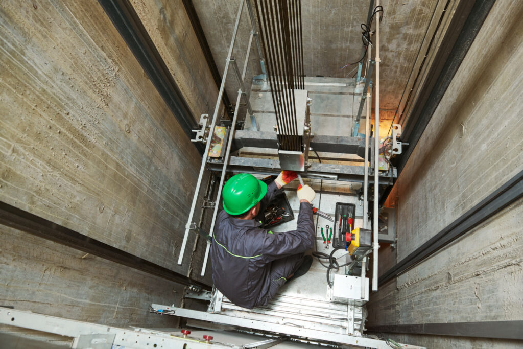 Elevator installation and maintenance. lift machinist worker adjusting elevator mechanism with spanners in shaft hoistway