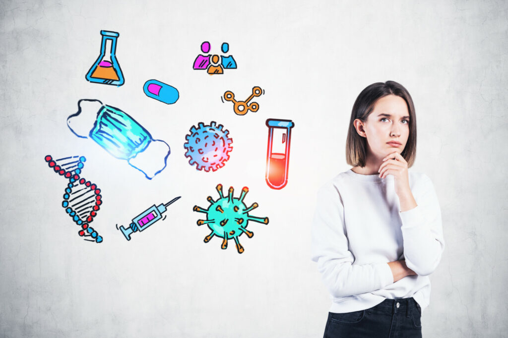 Pensive young woman standing near concrete wall with colorful medical sketch drawn on it. Concept of medicine and virus protection. Ncov Asian flu coronavirus