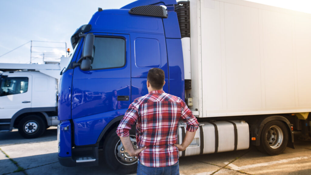 Professional middle aged truck driver in casual clothes looking at truck vehicle and going for a long transportation drive.
