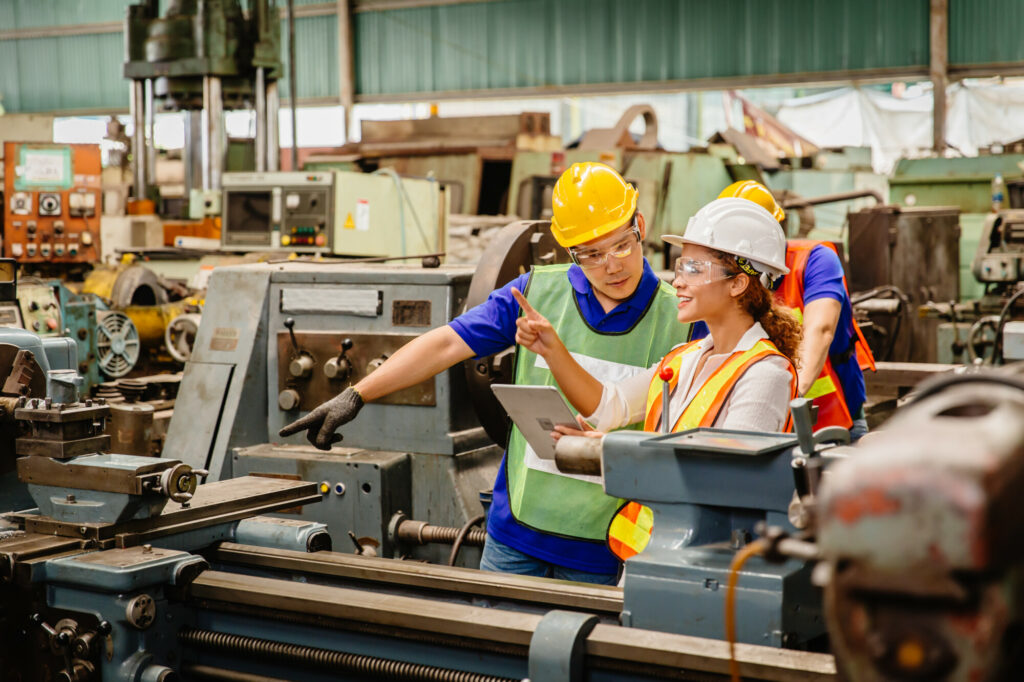 Mix race worker working together help each other to work in heavy industry machine wearing safty suit in factory production line.engineer with tablet coworking with team staff.