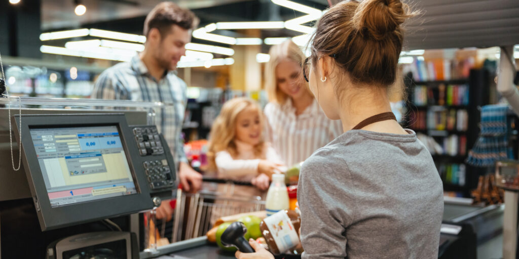 Beautiful family standing at the cash counter buying groceries at the supermarket